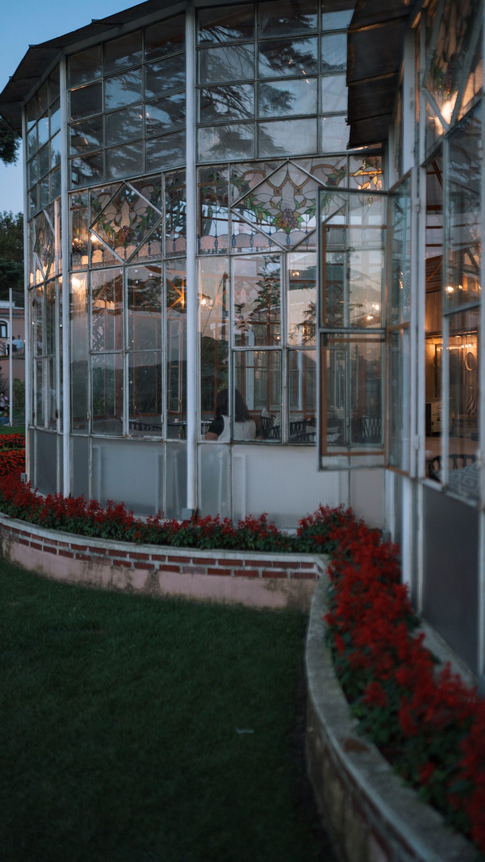 Glass conservatory glowing with evening light in a landscaped garden