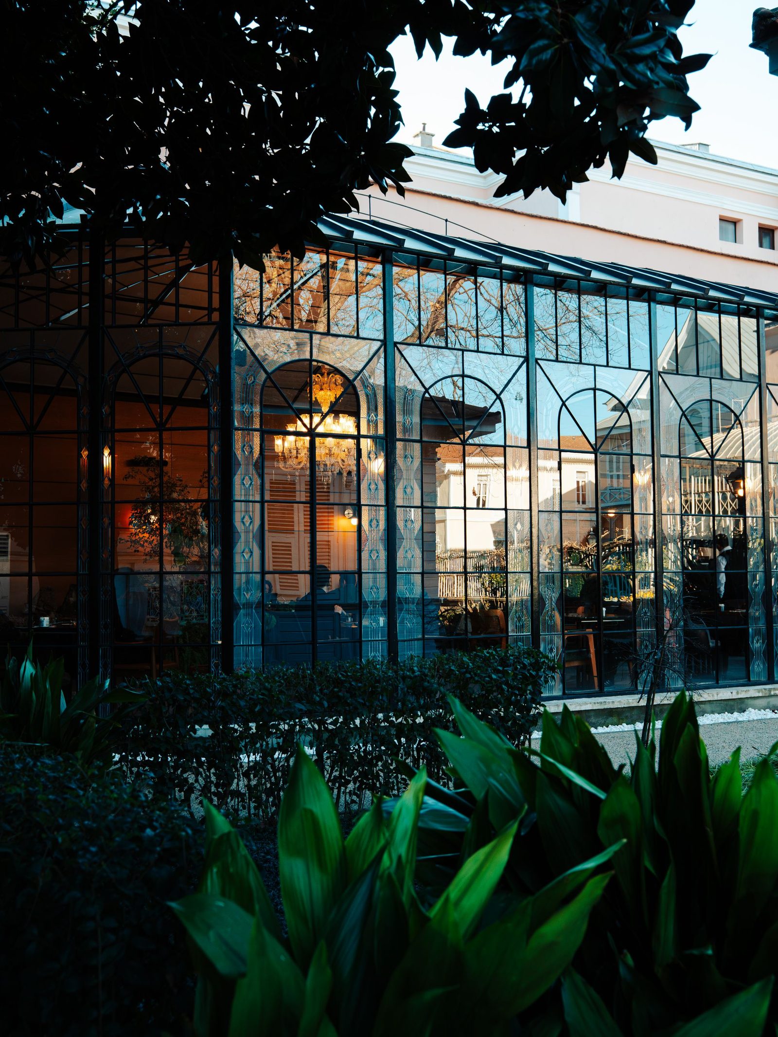 Tall glass gable front conservatory lit from inside at dusk